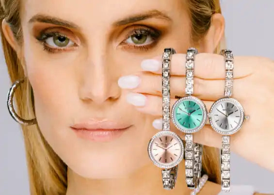 Una donna che modella tre orologi tempestati di cristalli con facce di diversi colori.