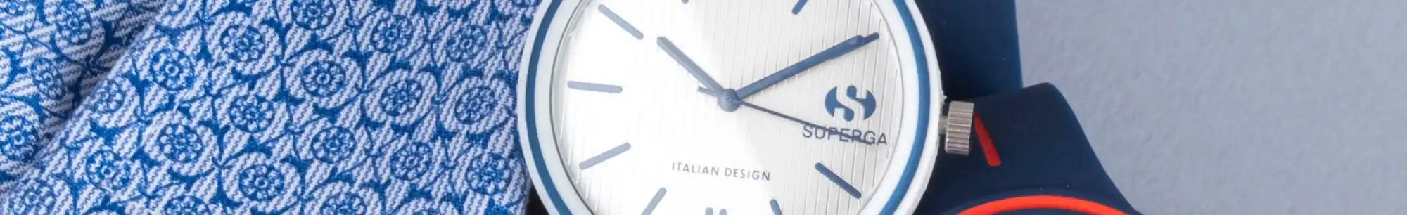 Un orologio da polso con faccia bianca, lunetta blu e lancette minuti/orario, e una banda blu con motivo.